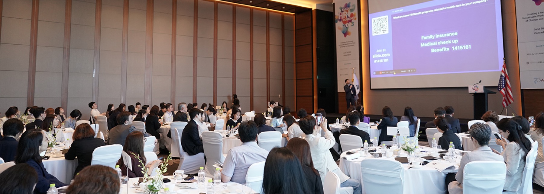 A full ballroom at an AMCHAM Korea workshop, with the Korean and United States flags beside the stage